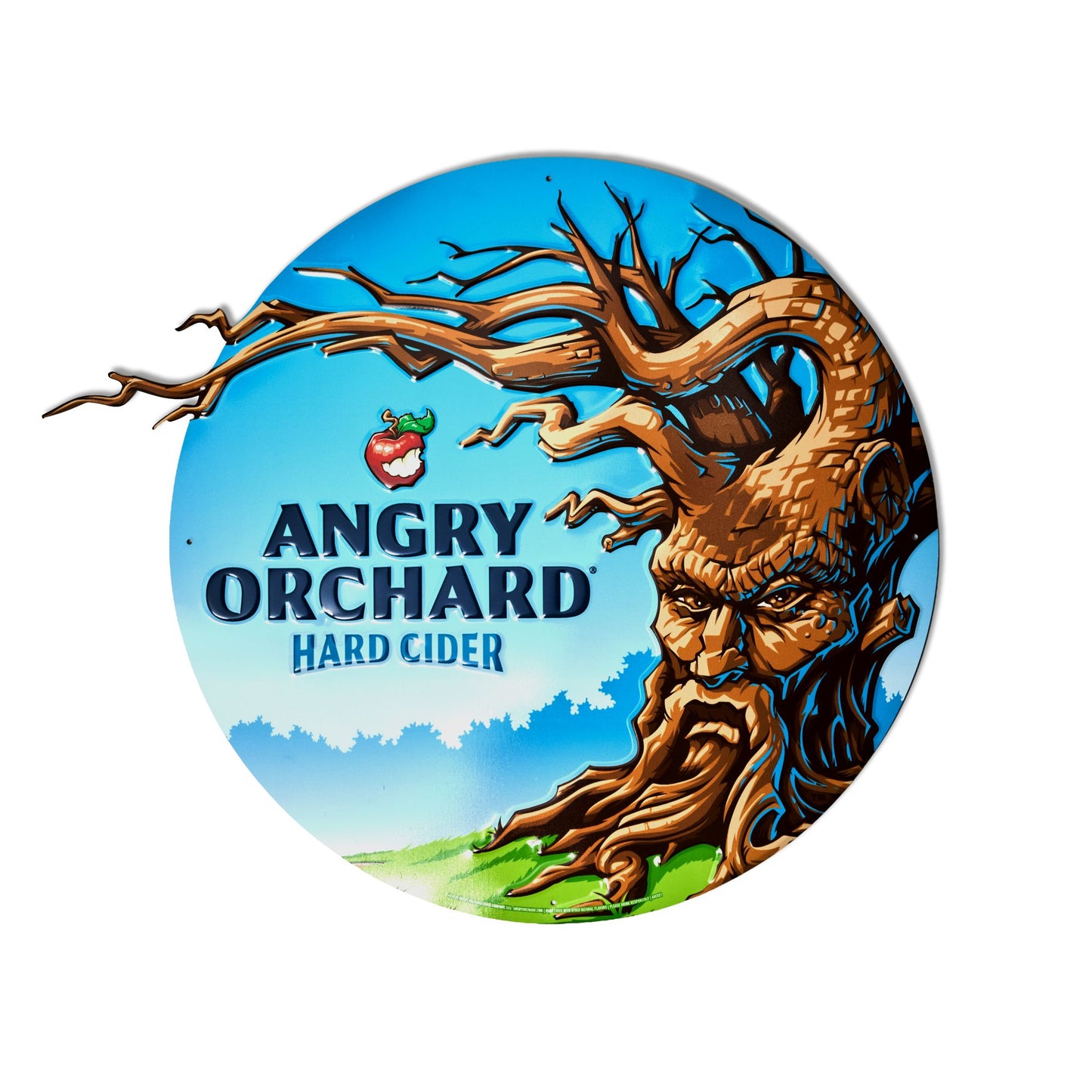 A circular vintage-style metal sign for Angry Orchard Hard Cider, featuring a detailed illustration of a tree with a face and roots, set against a bright blue sky with green grass.