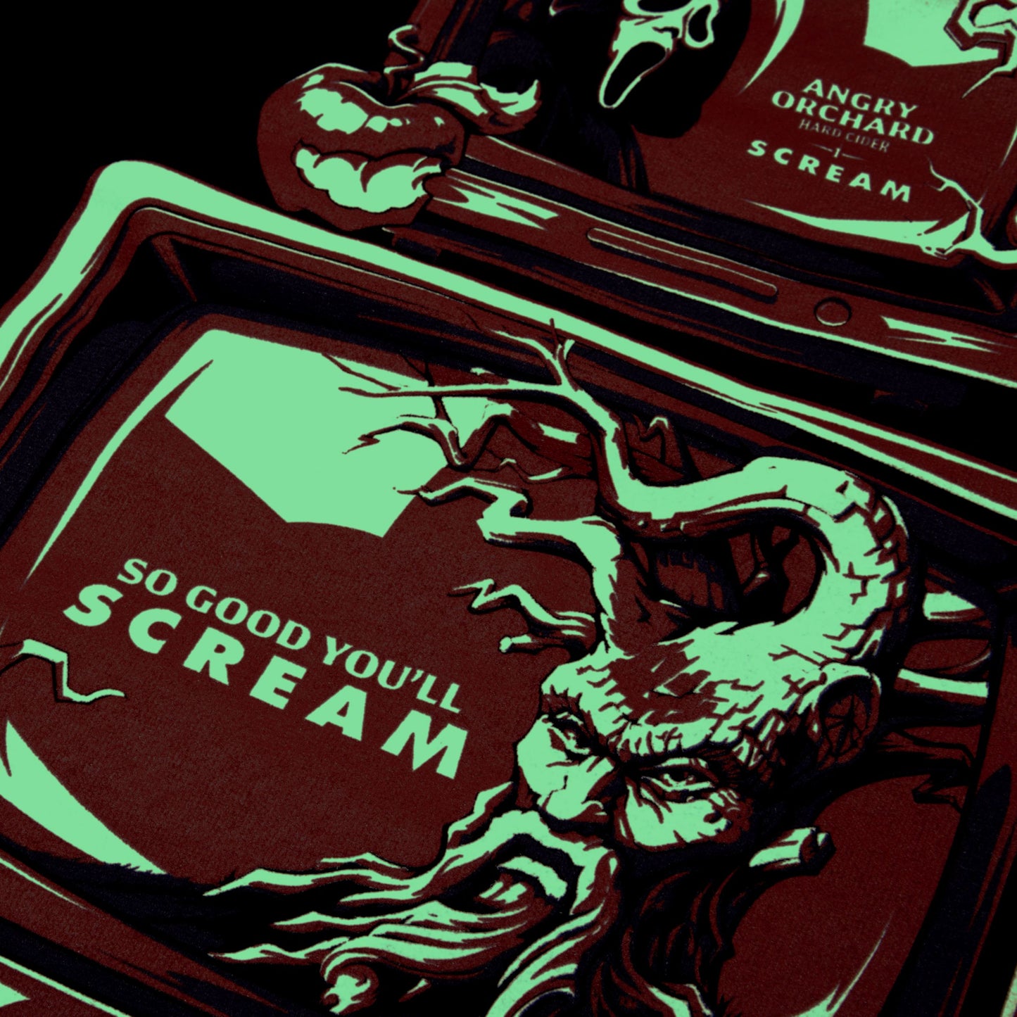 A stylized graphic print featuring a horror-themed illustrated face and text reading 'SO GOOD YOU'LL SCREAM' on a dark red background, with additional matching artwork above and the visible text 'ANGRY ORCHARD HARD CIDER SCREAM'.