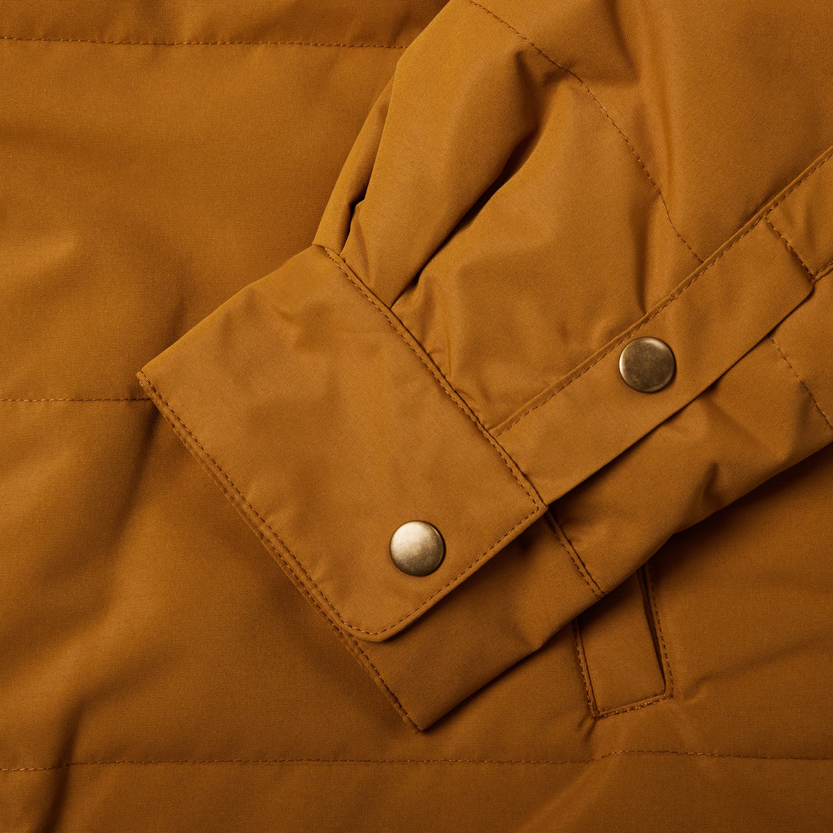 Brown button up jacket sleeve with two brass buttons on sleeve.