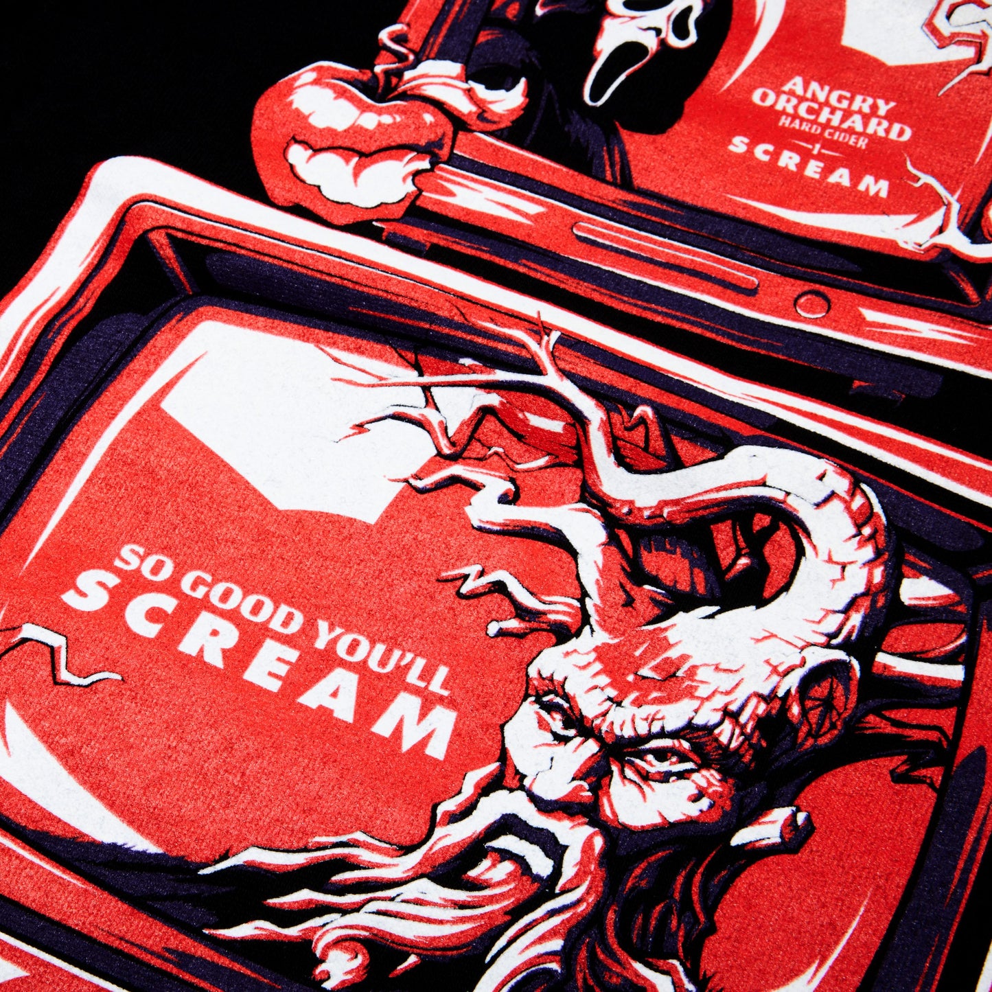 A close-up of a red graphic print featuring a stylized screaming face and the text 'SO GOOD YOU'LL SCREAM' on a black background, with part of another red graphic reading 'ANGRY ORCHARD HARD CIDER SCREAM' visible at the top.