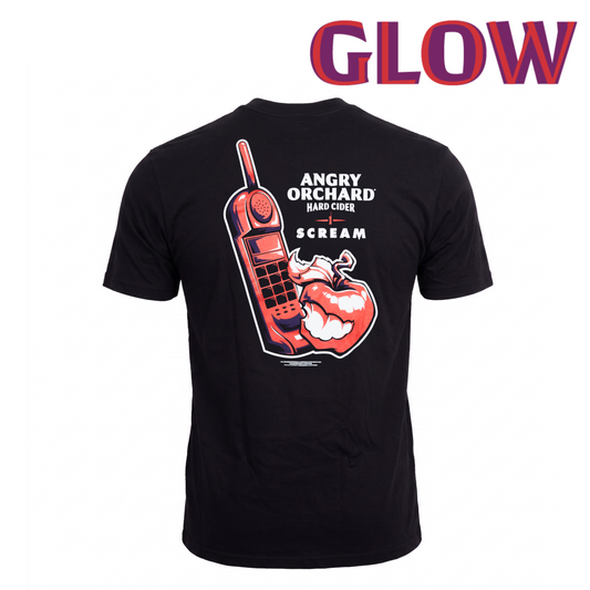 A black short-sleeve t-shirt shown from the back, featuring a large graphic print of a red mobile phone, a red apple with a horn, and white text reading 'ANGRY ORCHARD HARD CIDERSCREAM'. The word 'GLOW' is written in large red and purple letters at the top of the image.