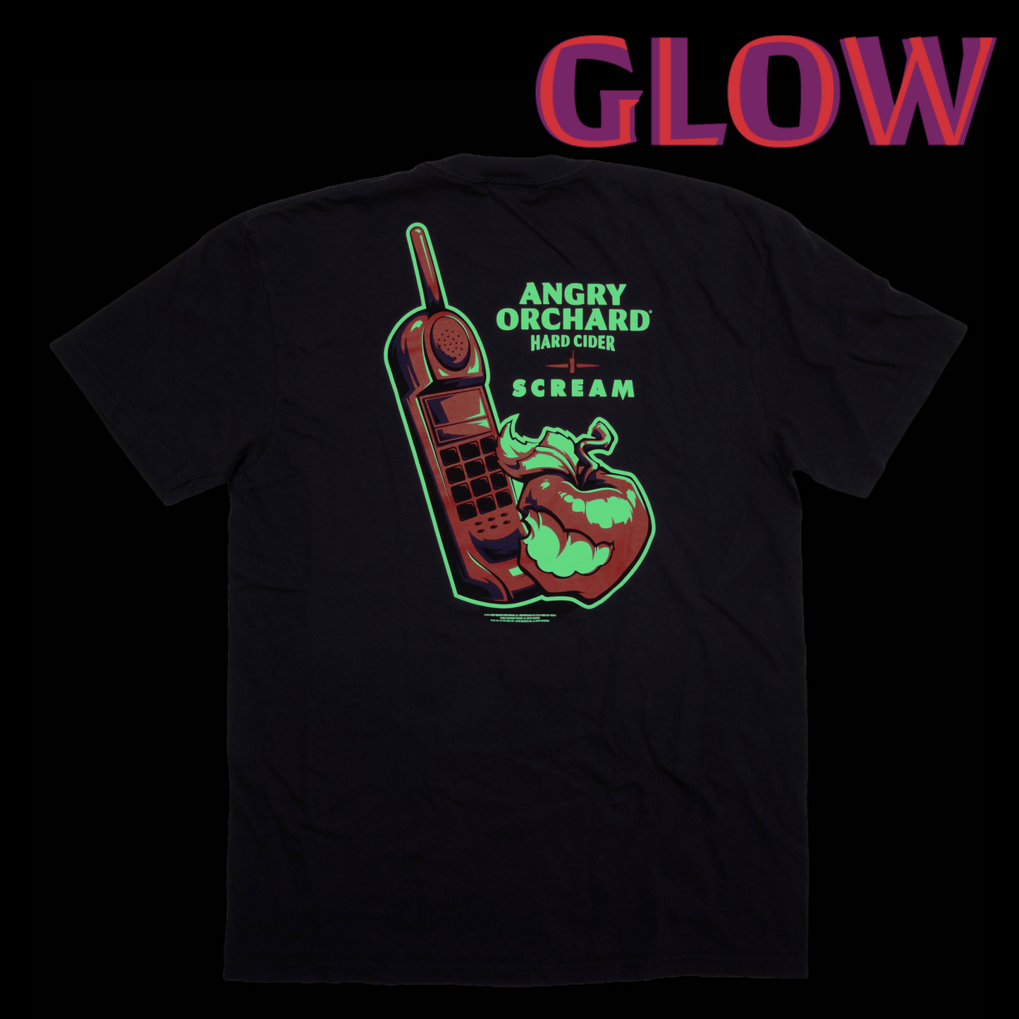 A black short-sleeve t-shirt shown from the back, featuring a graphic of a red mobile phone and a red chili pepper with green neon-style outlines and text reading 'ANGRY ORCHARD HARD CIDER SCREAM'. The word 'GLOW' appears in large pink-to-purple gradient letters at the top on a black background.