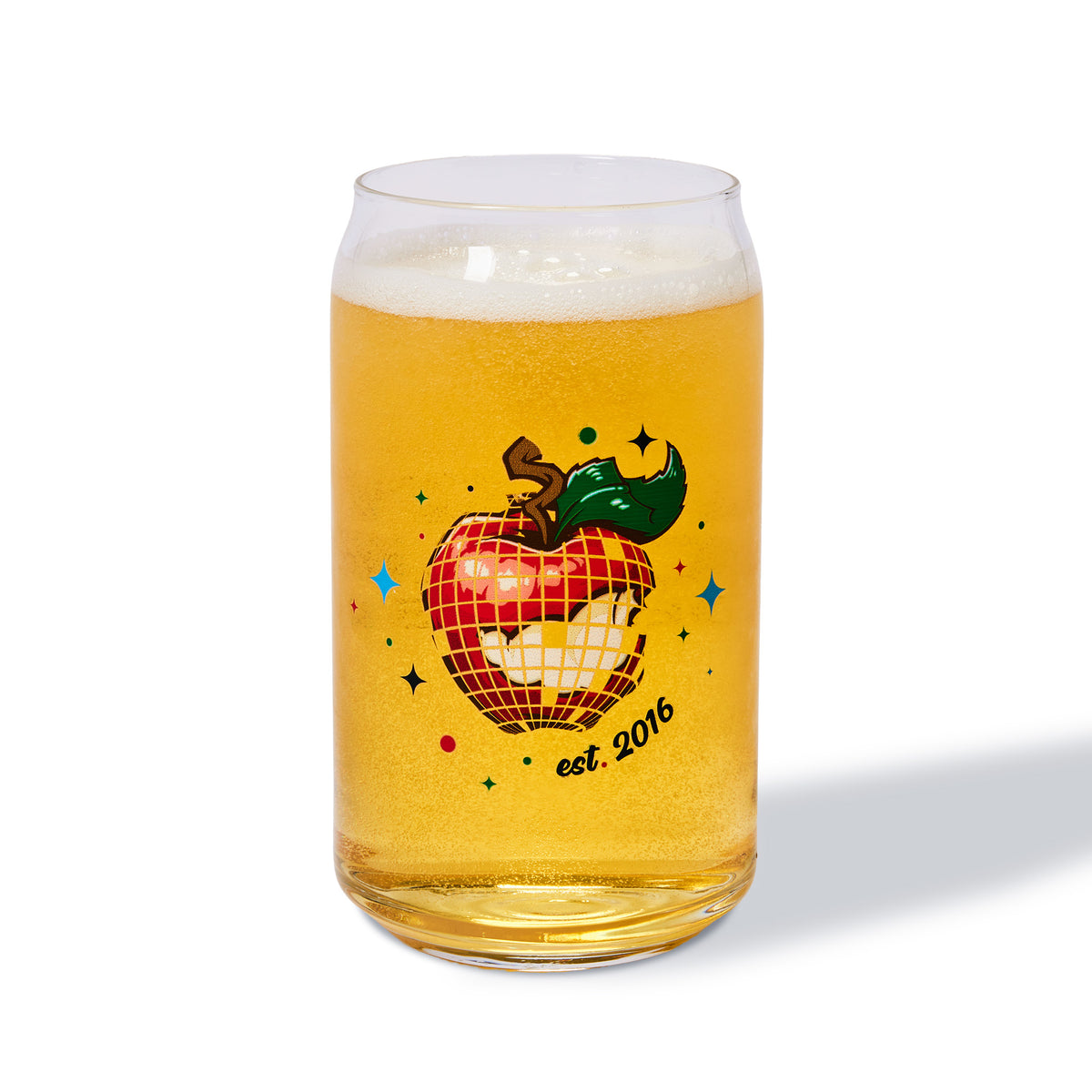 A clear glass can-shaped tumbler filled with golden beer, featuring a retro graphic of a red apple with a disco ball pattern, a green pepper, and the text 'est. 2016' on a white background.